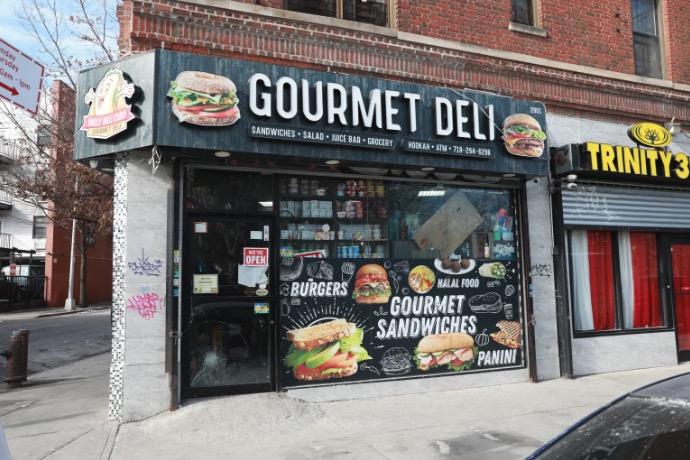 A Gourmet Deli storefront with a shattered door pane.