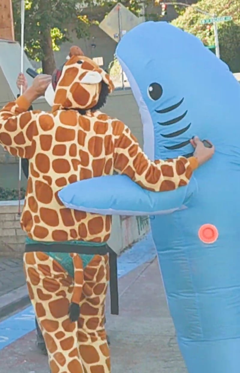 Robby Roadsteamer hugging a shark after being shot as he continued to goad ICE officers from the sidewalk.