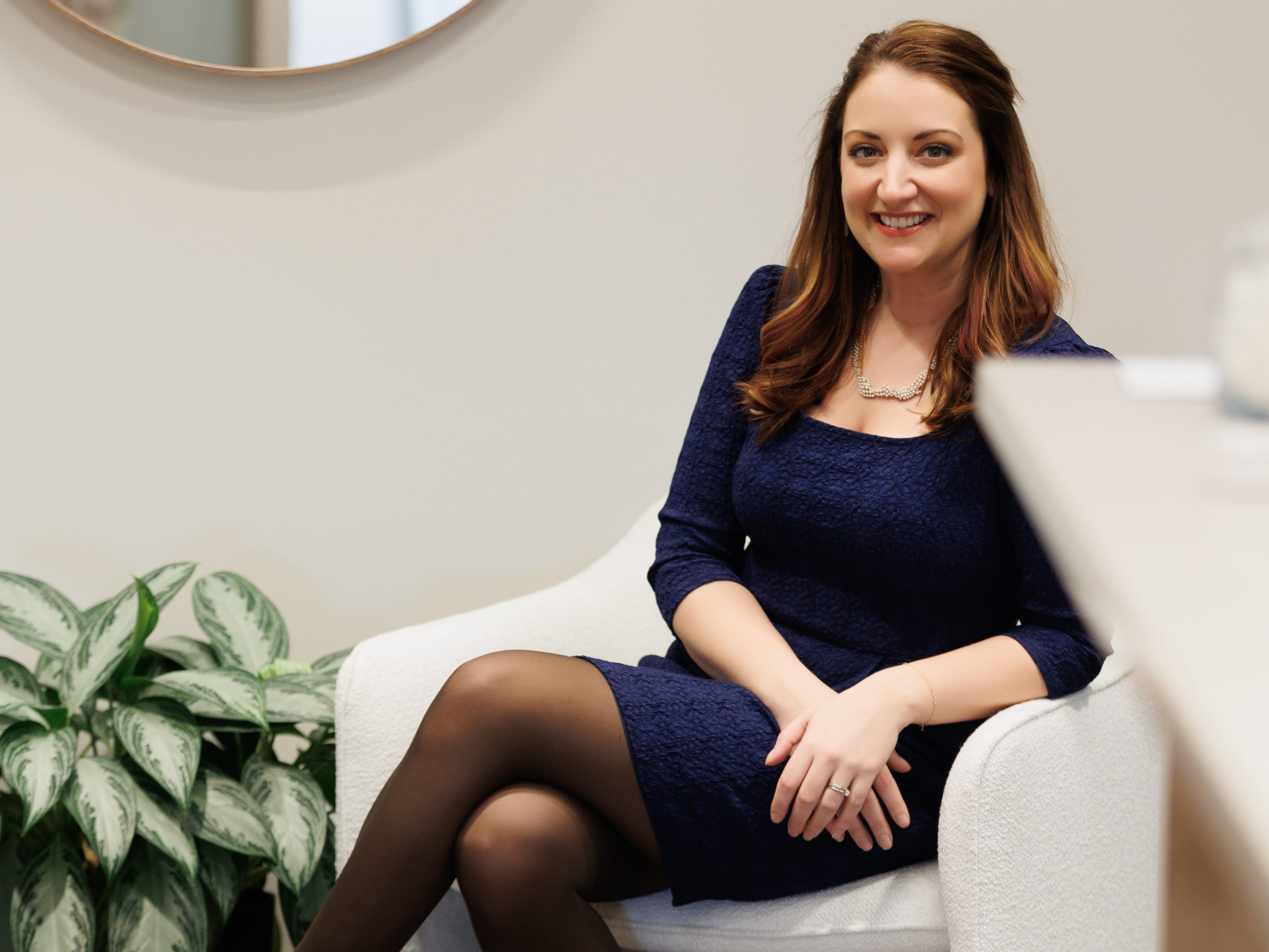 woman in professional blue dress sitting in white chair
