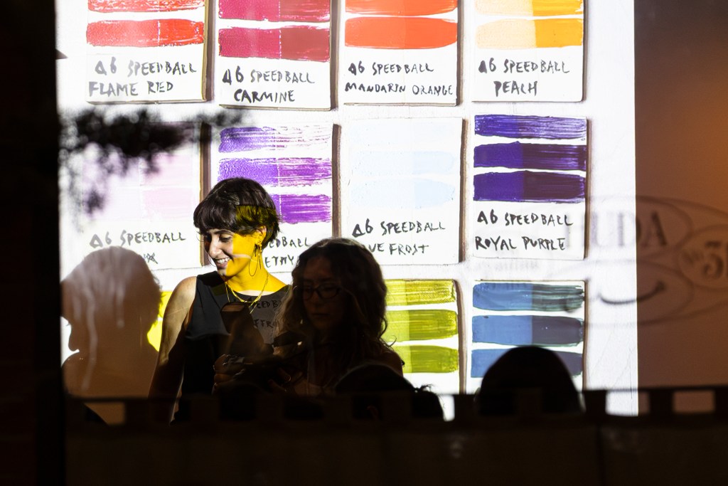 A woman teaching an art class in front of swatches of Speedball paint.