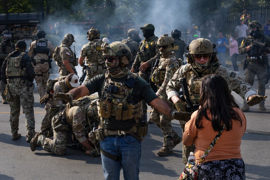 Police take two people into custody, as tear gas fills the air after it was used by federal law enforcement agents who were being confronted by community members and activists for reportedly shooting a woman in the Brighton Park neighborhood on October 04, 2025 in Broadview, Illinois.