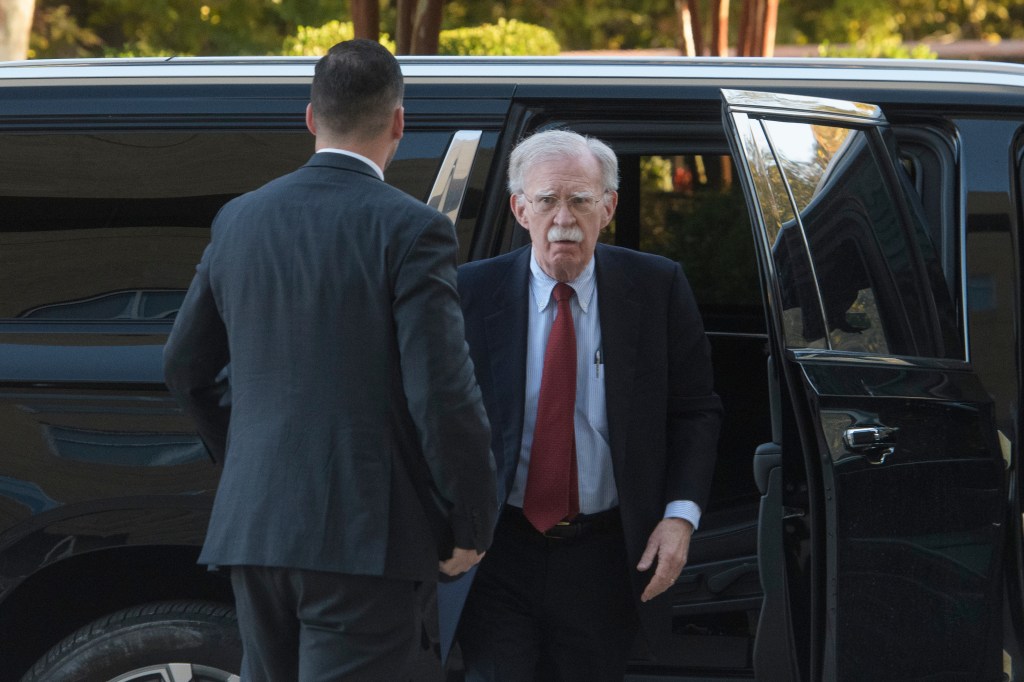 Former Trump administration national security adviser John Bolton exiting a black vehicle.