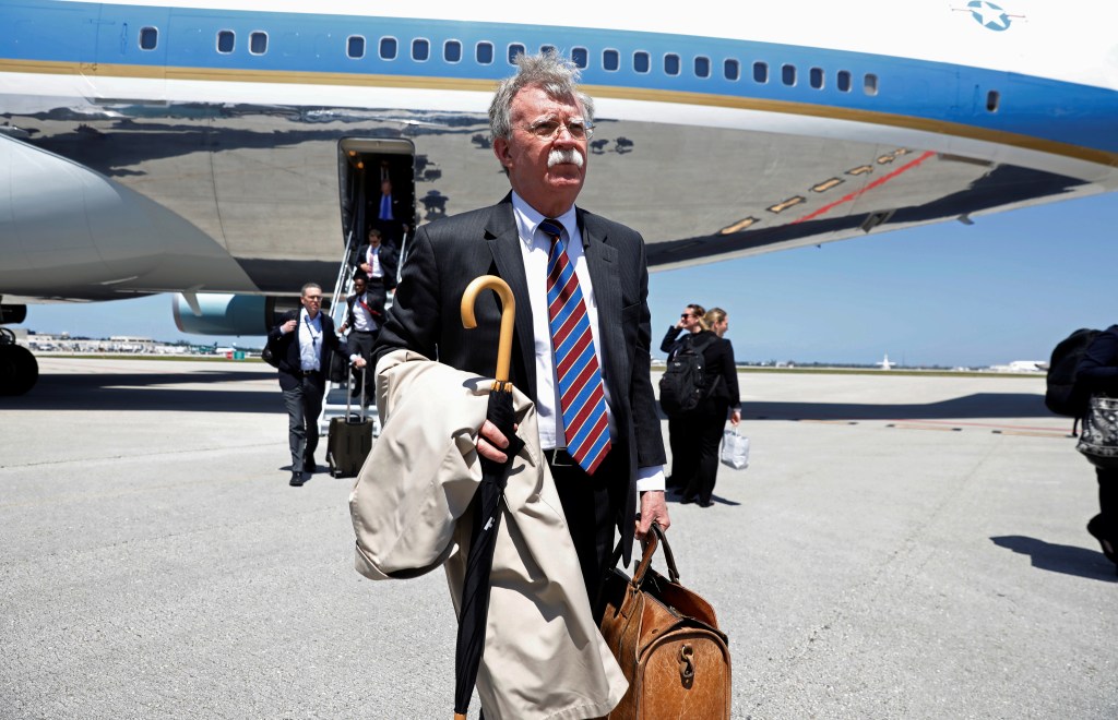 White House National Security Advisor John Bolton steps off Air Force One carrying a trench coat and umbrella.
