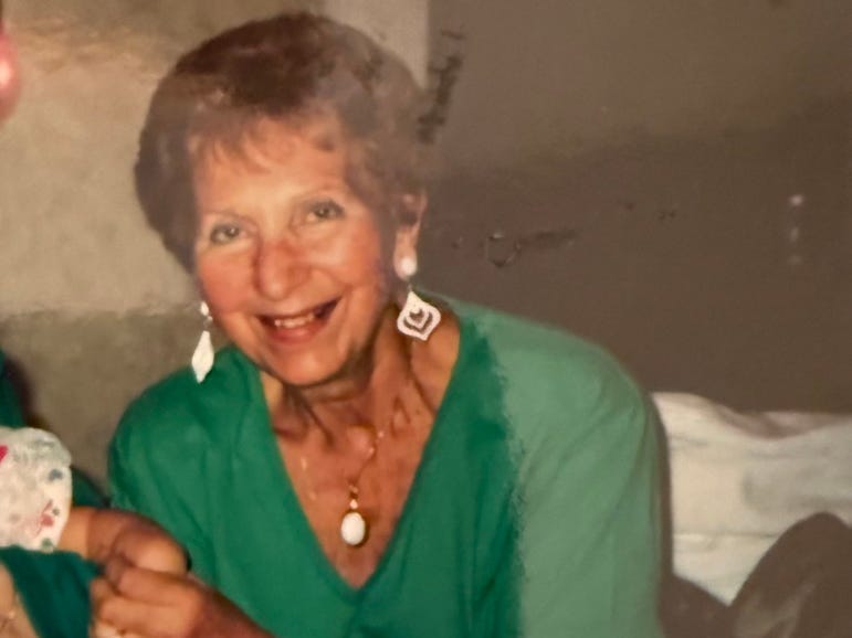 Photo of woman with earrings, green shirt, colorful skirt