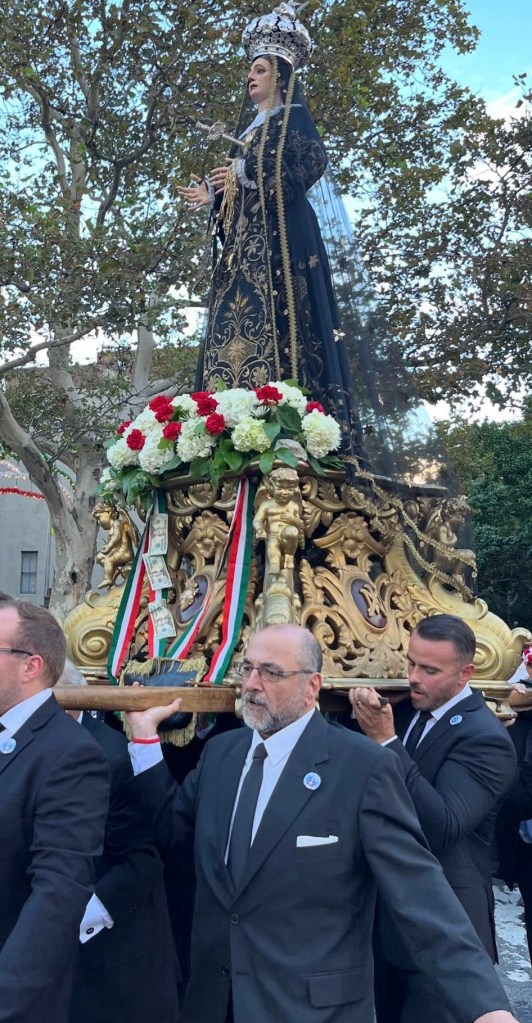 Men carrying a statue of Our Lady of Sorrows decorated with money and flowers.