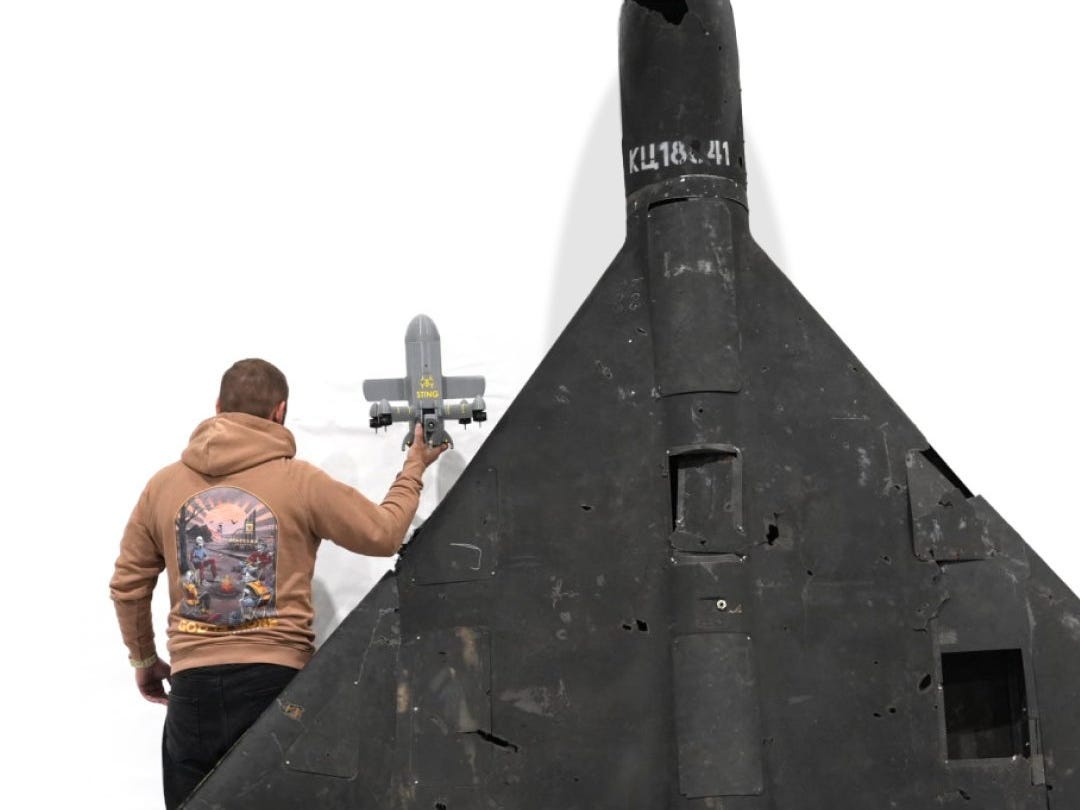 A man holds up the Sting for a size comparison with a downed Shahed drone.