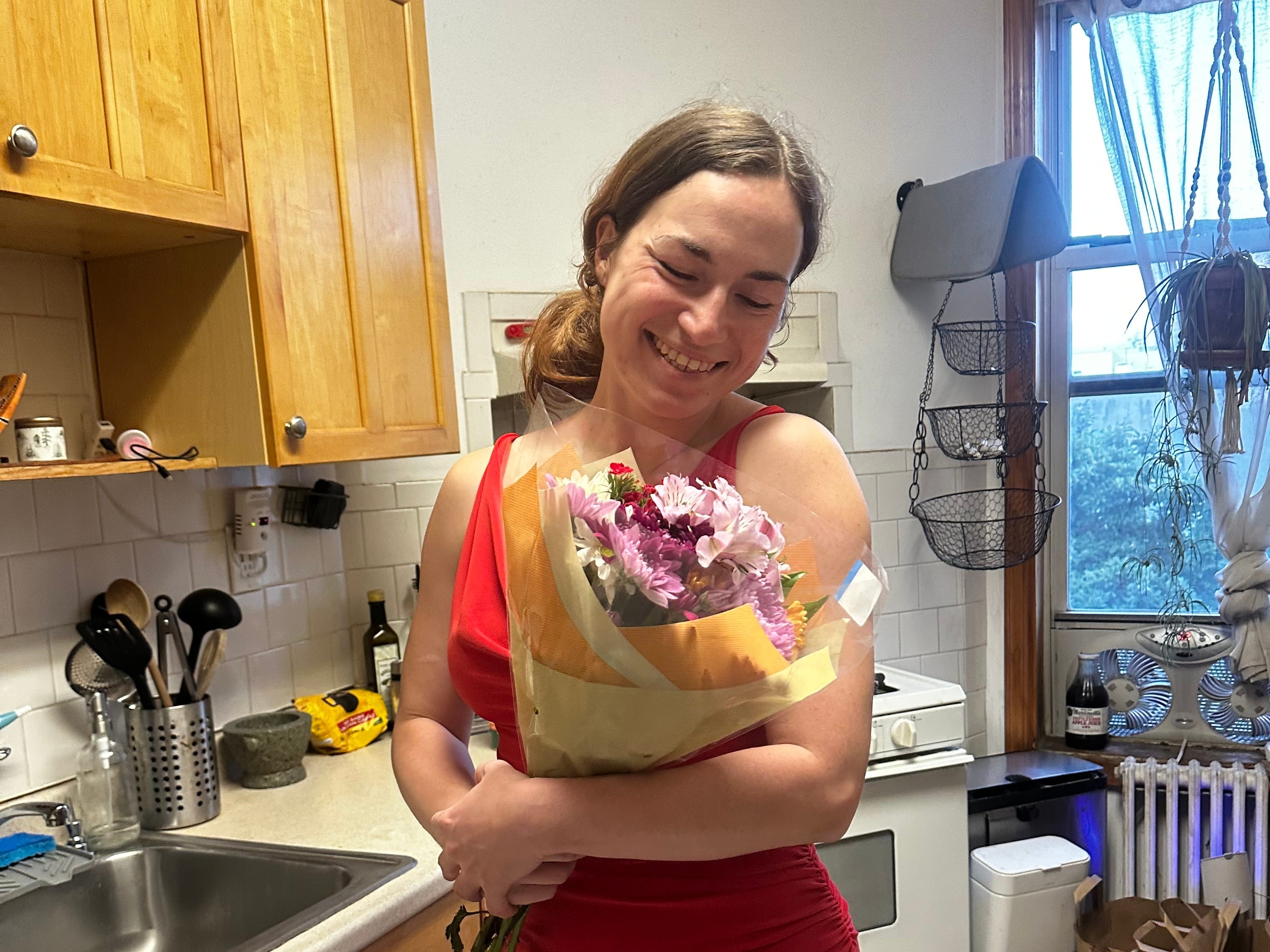 The author holding a bouquet in a kitchen in New York.