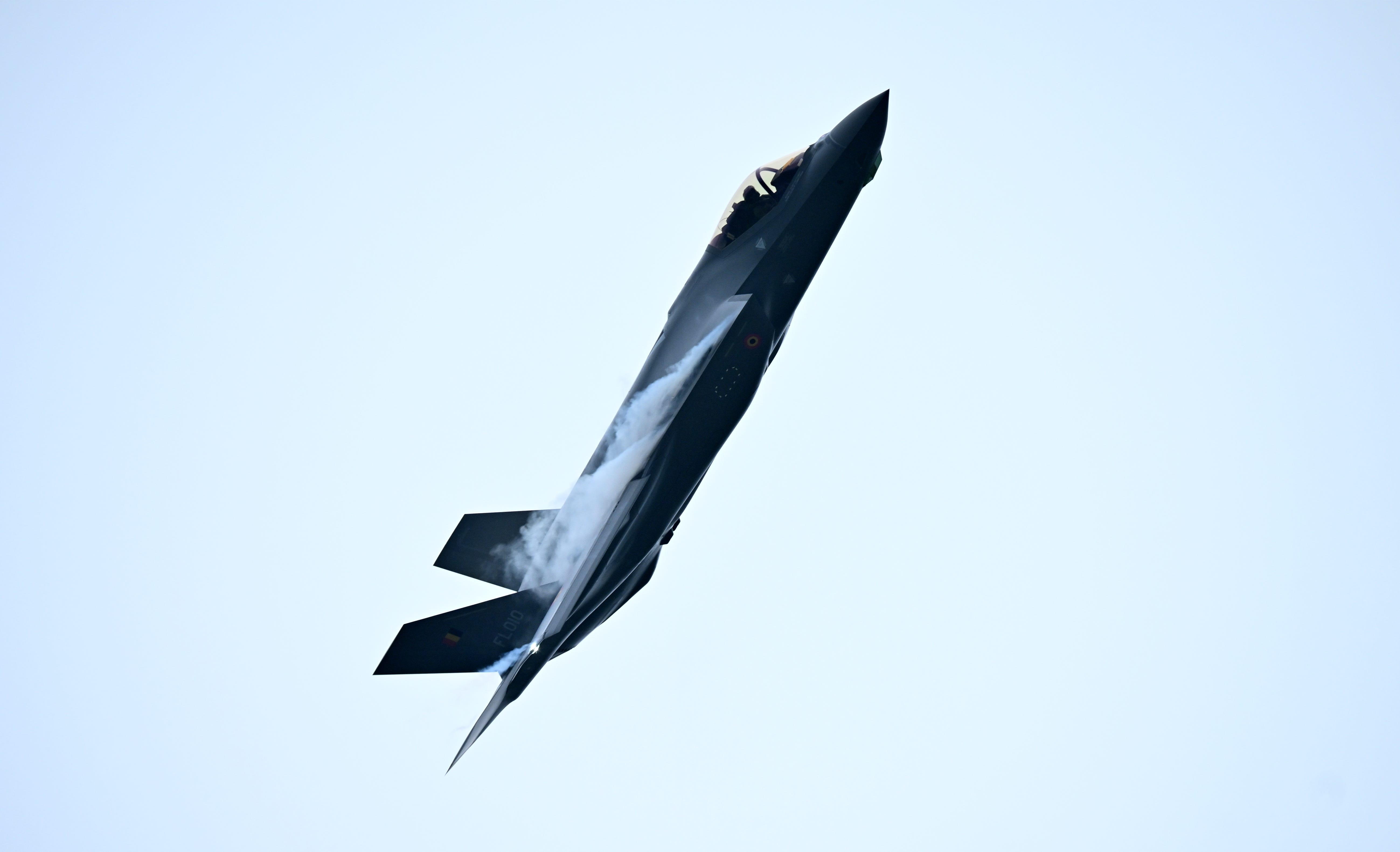 A grey fighter jet points up in the sky