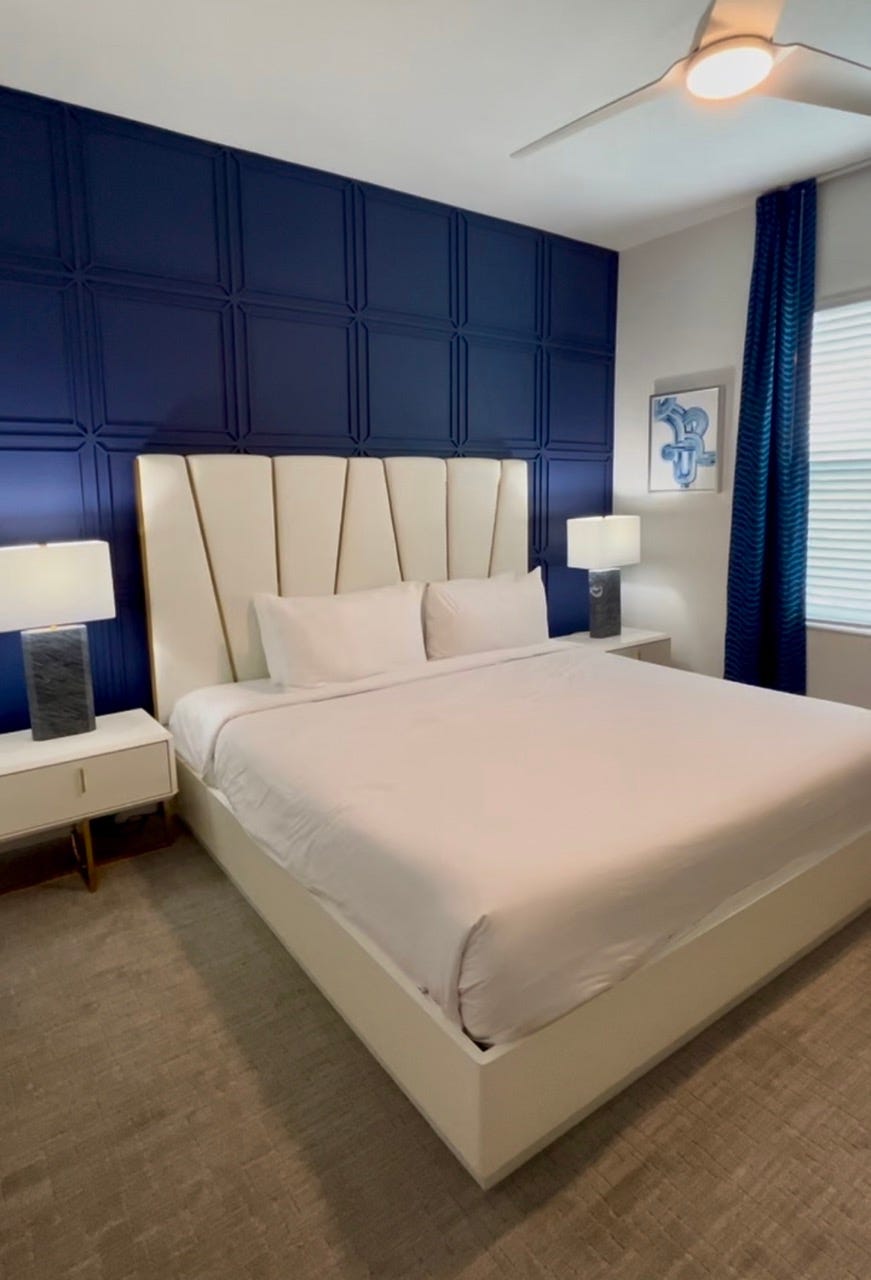 White headboard in front of blue wall with nightstands next to it