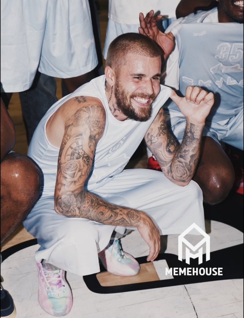 Justin Bieber smiling and crouching on a basketball court.