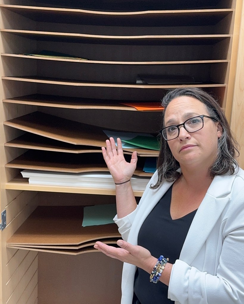 Manhattan high school teacher Erica Yonks gestures her hands toward an empty supply shelf
