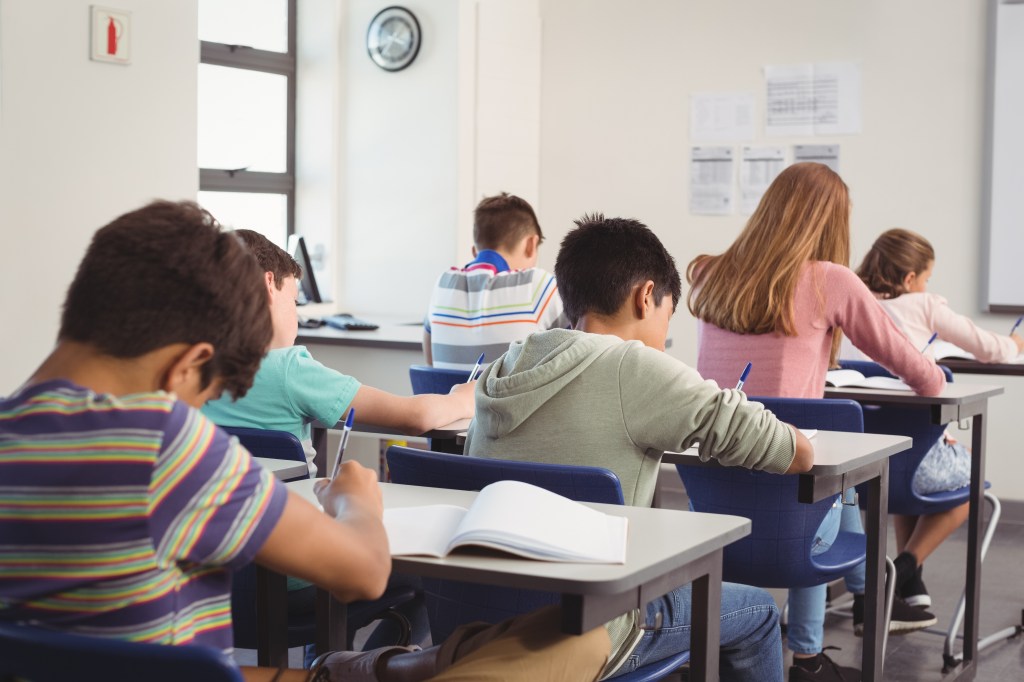 Students in a classroom working on homework at their desks.