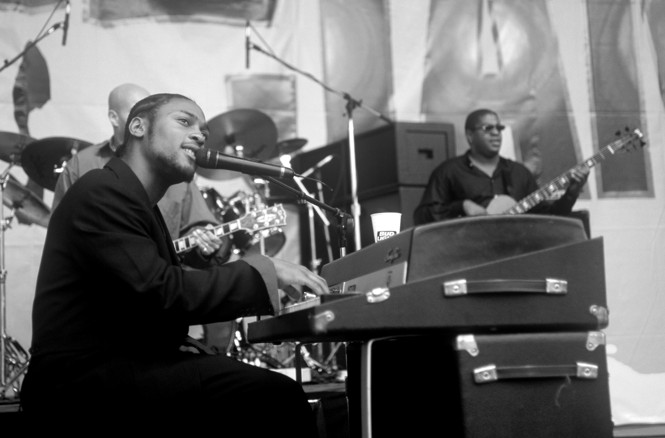 A black and white photo of D'Angelo at the piano during a live concert