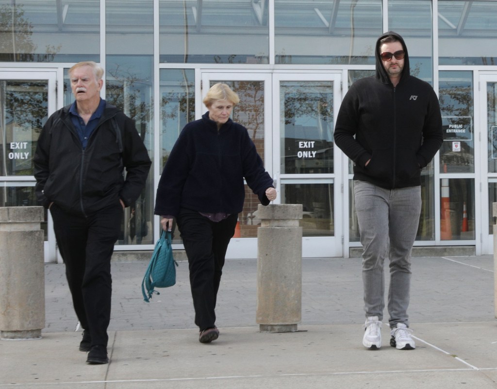 Teacher Mark Verity, wearing a black hoodie and sunglasses, walks out of First District Court with his parents after being arraigned Oct. 18, 2025