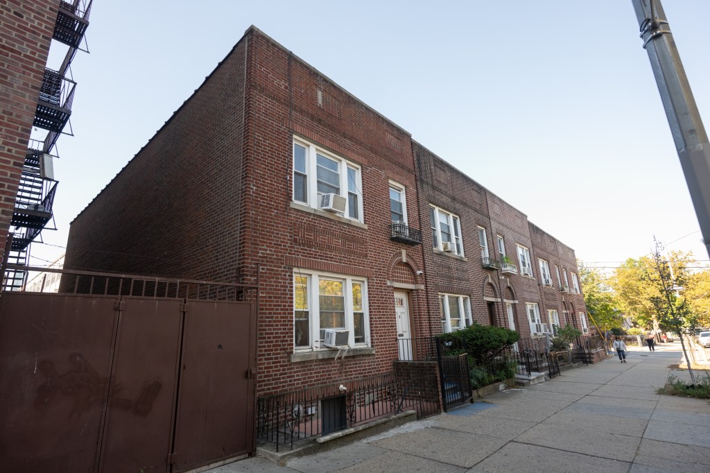 Red brick building with a gated entrance and a sidewalk, Queens, NY.