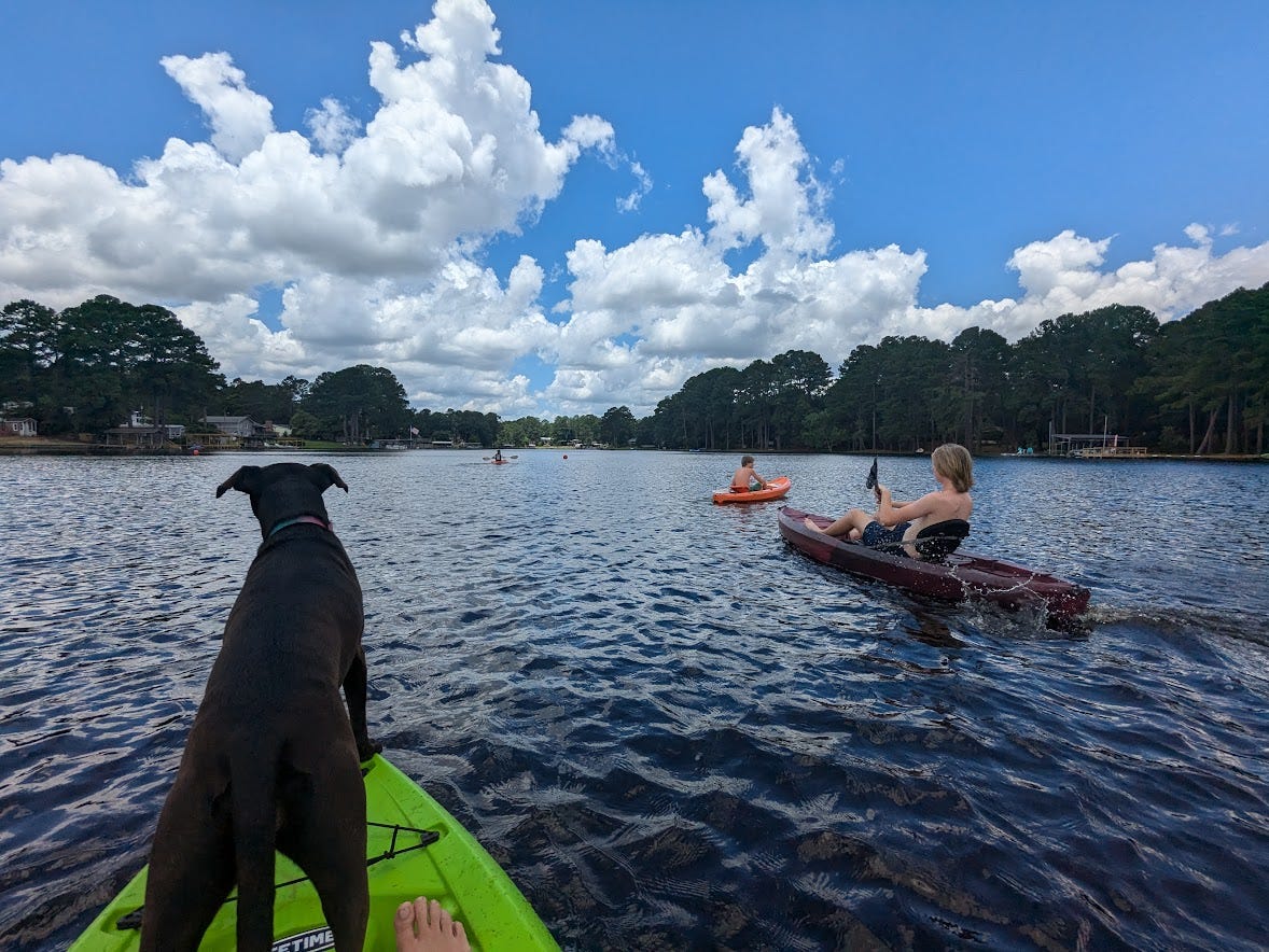 The authors family and dog are shown kayaking on a lake they live beside.