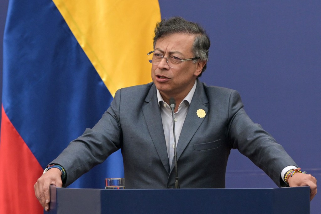 Colombia's President Gustavo Petro speaking at a podium with the Colombian flag in the background.