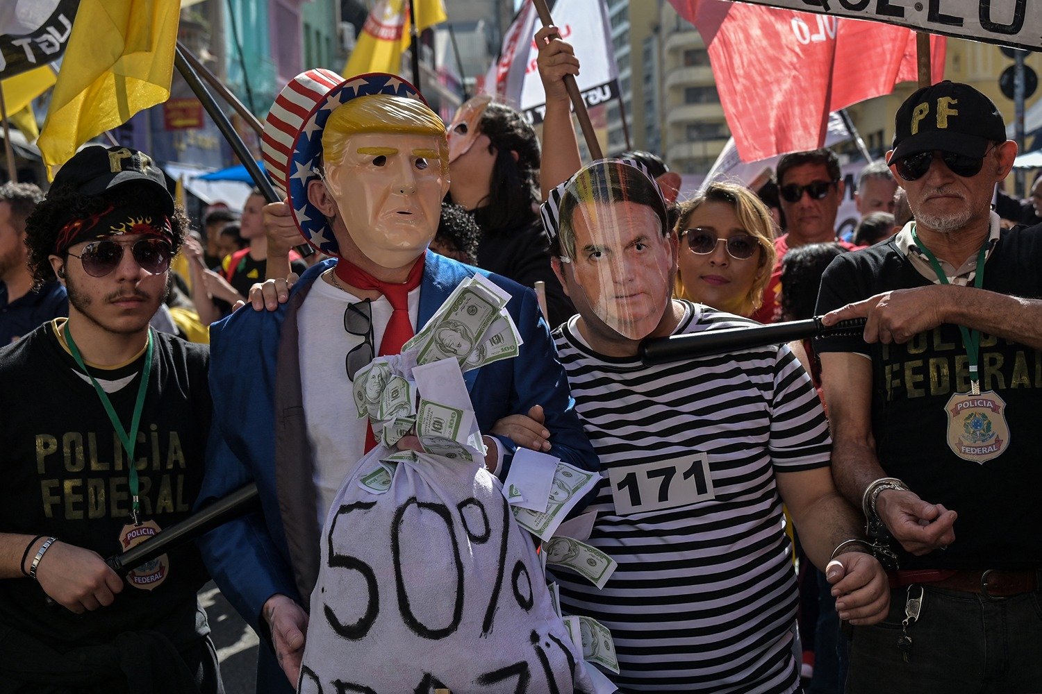 Protesters wear masks of Trump (left) and Bolsonaro (right).