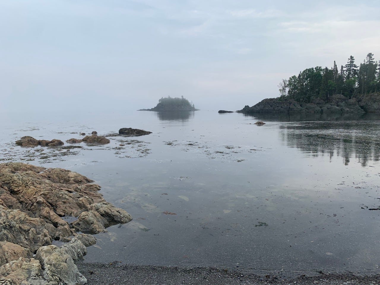 View of water, rocks, below foggy sky