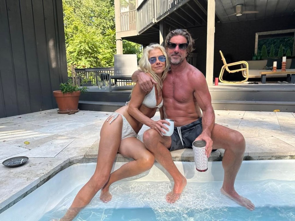 Brett James and Melody Wilson sitting by a pool with their feet in the water.