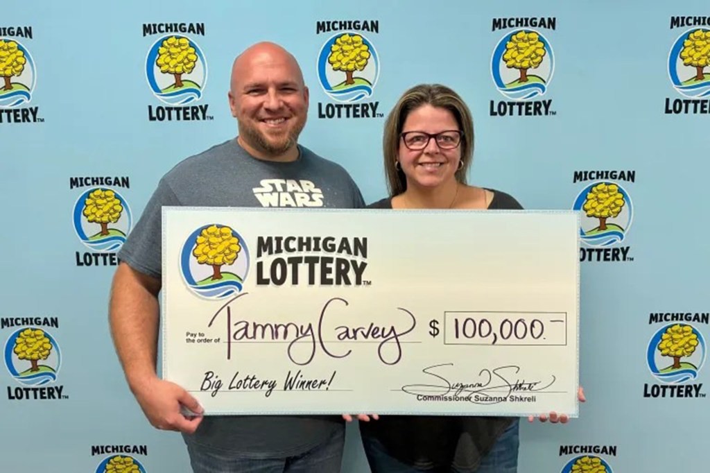 Tammy Carvey holding a Michigan Lottery check for $100,000.