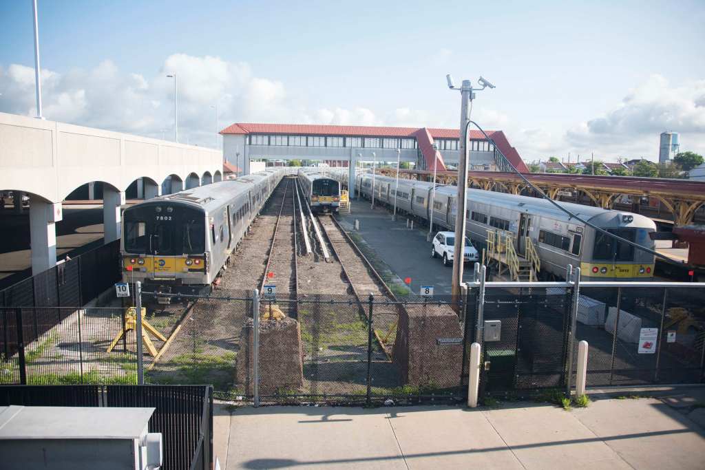 Long Island Rail Road trains stopped at the Long Beach station, with an overhead pedestrian bridge.