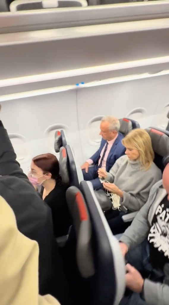 Robert F. Kennedy Jr. and Cheryl Hines sitting in economy seats on an airplane.