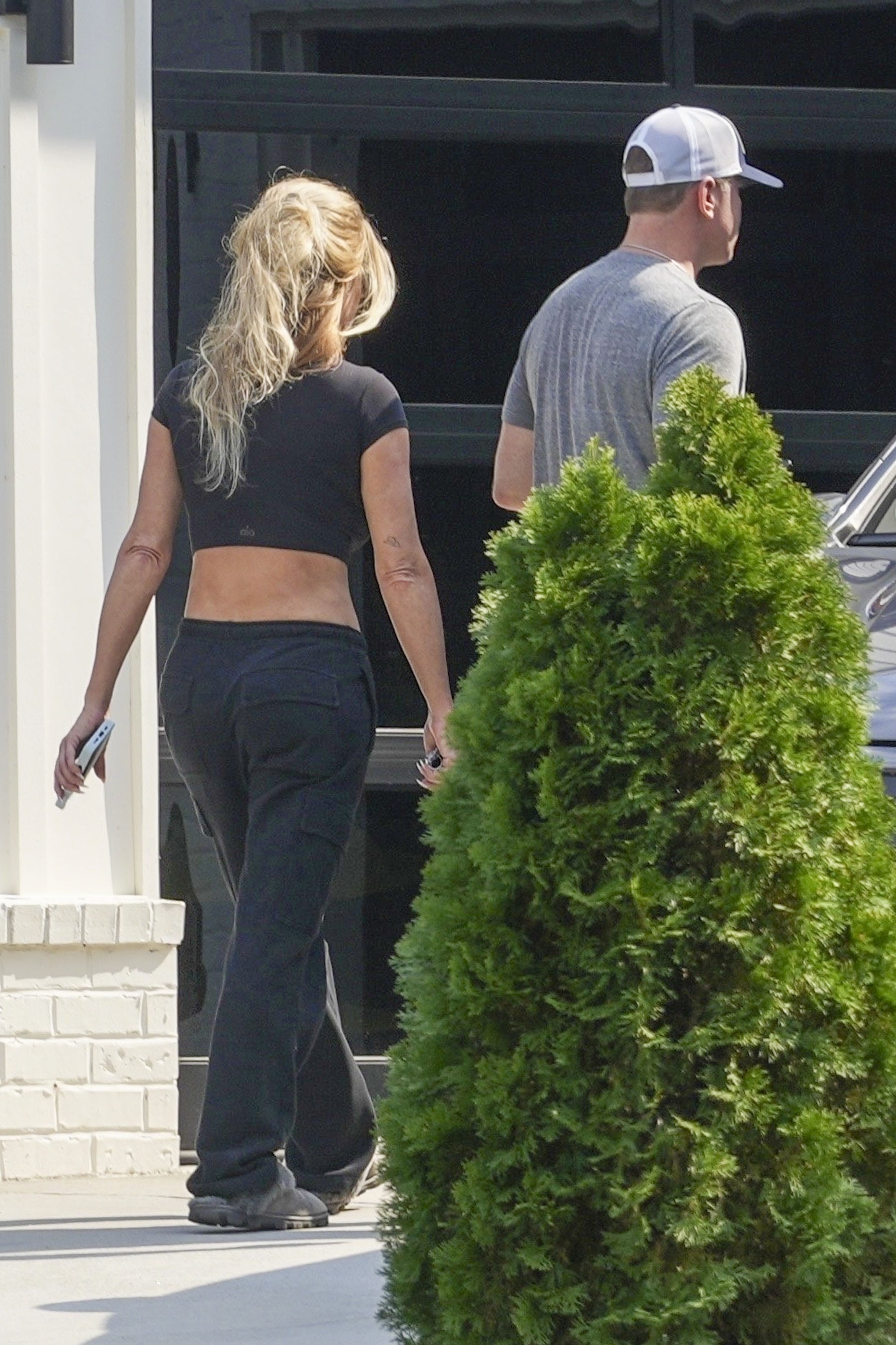 Kim Zolciak and Kyle Mowitz from behind, walking away from a house.