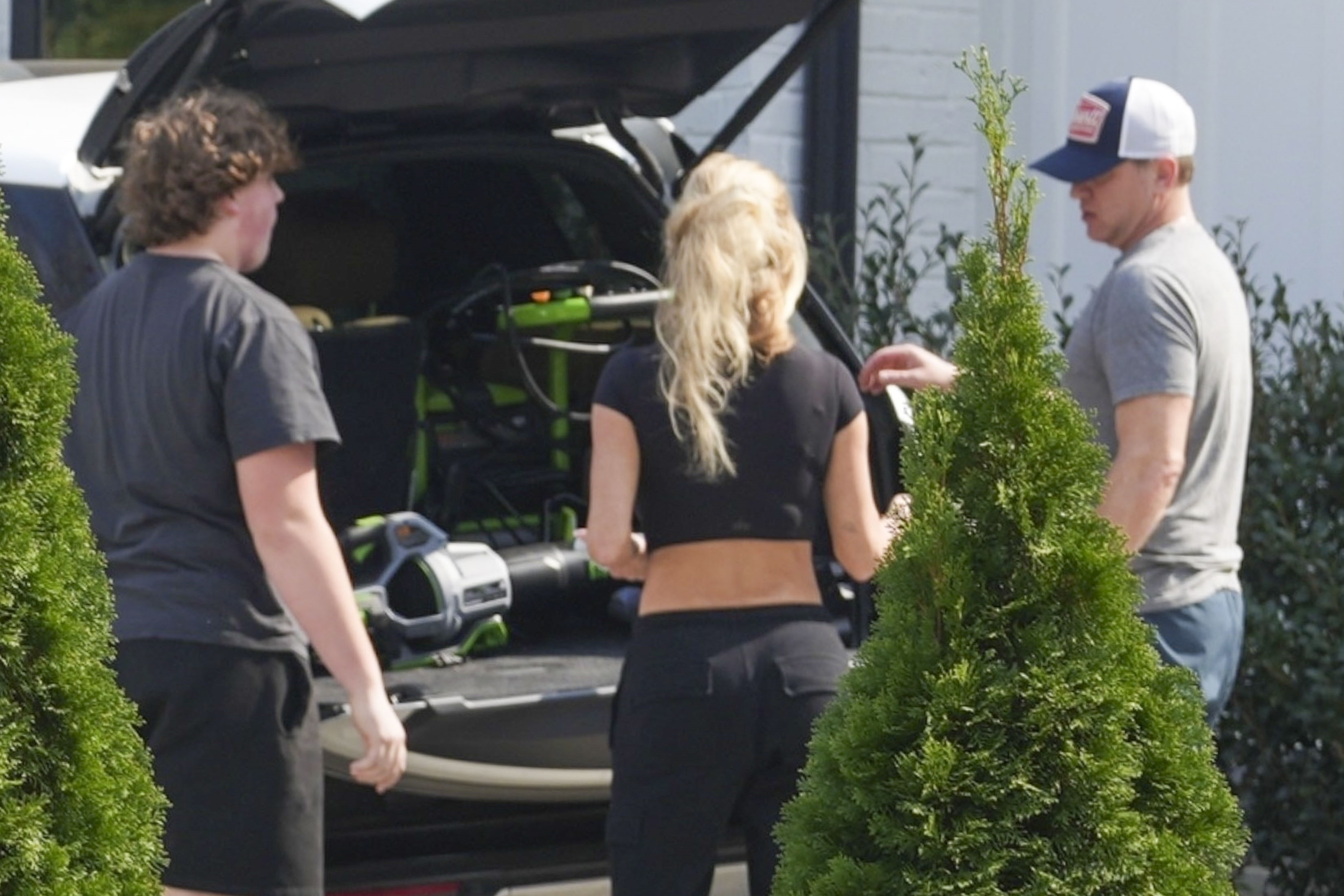 Kim Zolciak and Kyle Mowitz at his house, with a young man next to an open car trunk.