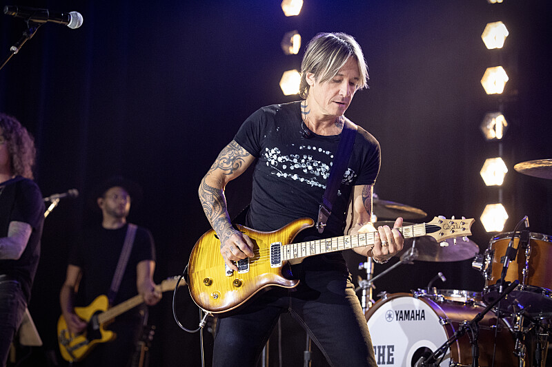 Keith Urban playing an electric guitar on stage.