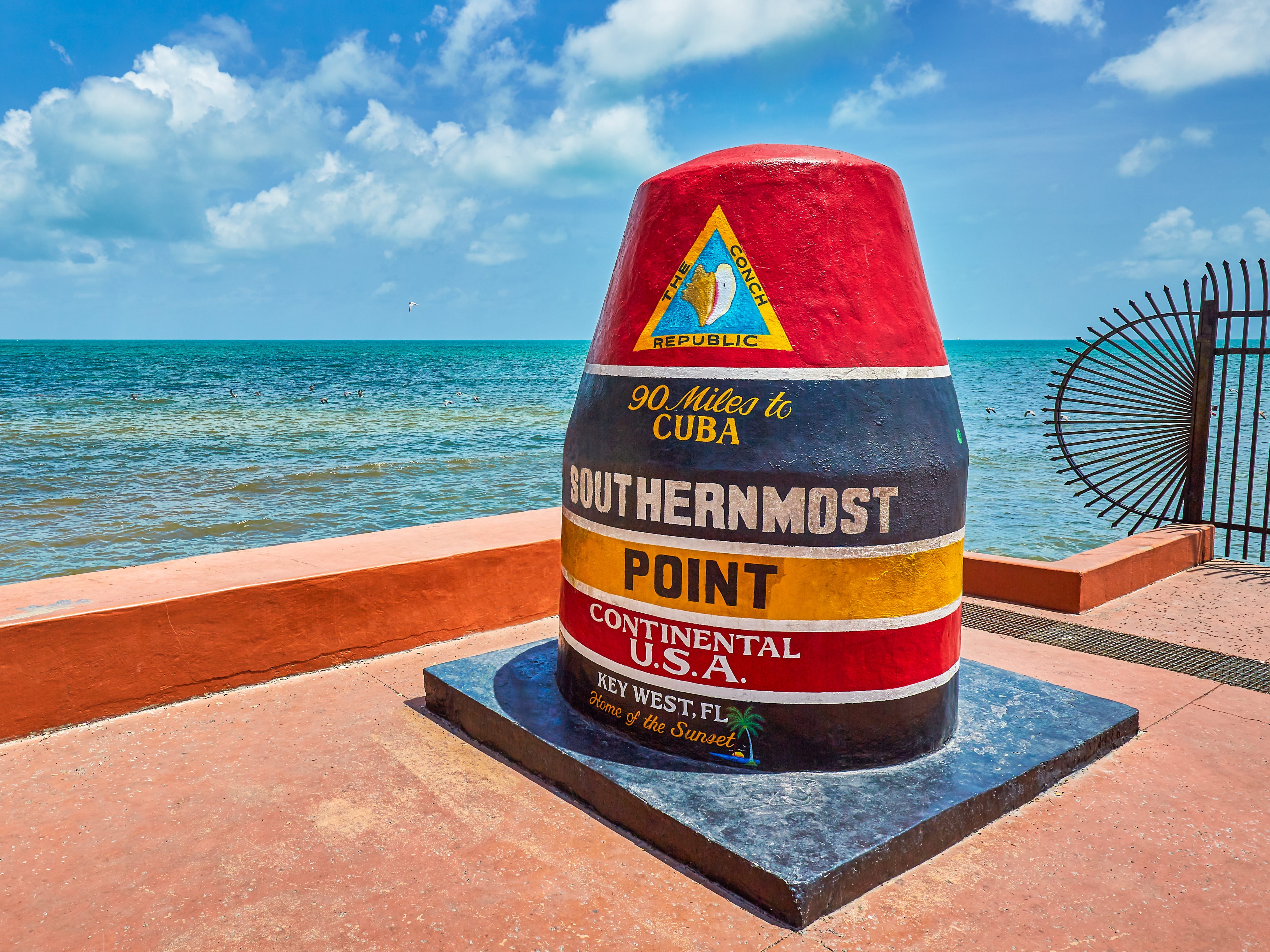 A painted marker at the Southernmost point in the Continental United States, with the ocean in the background.