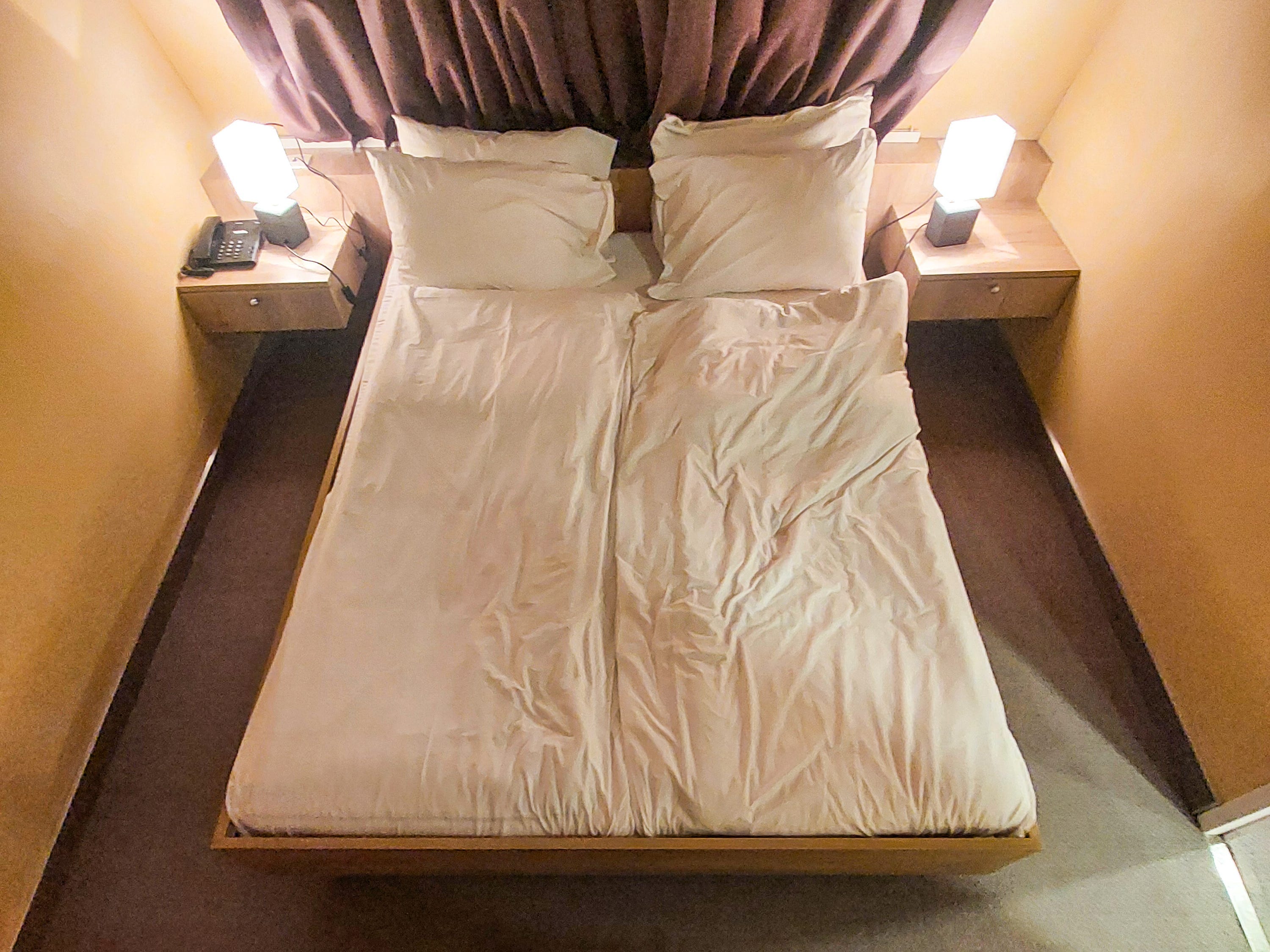 A queen-size bed with nightstands and lamps on each side.