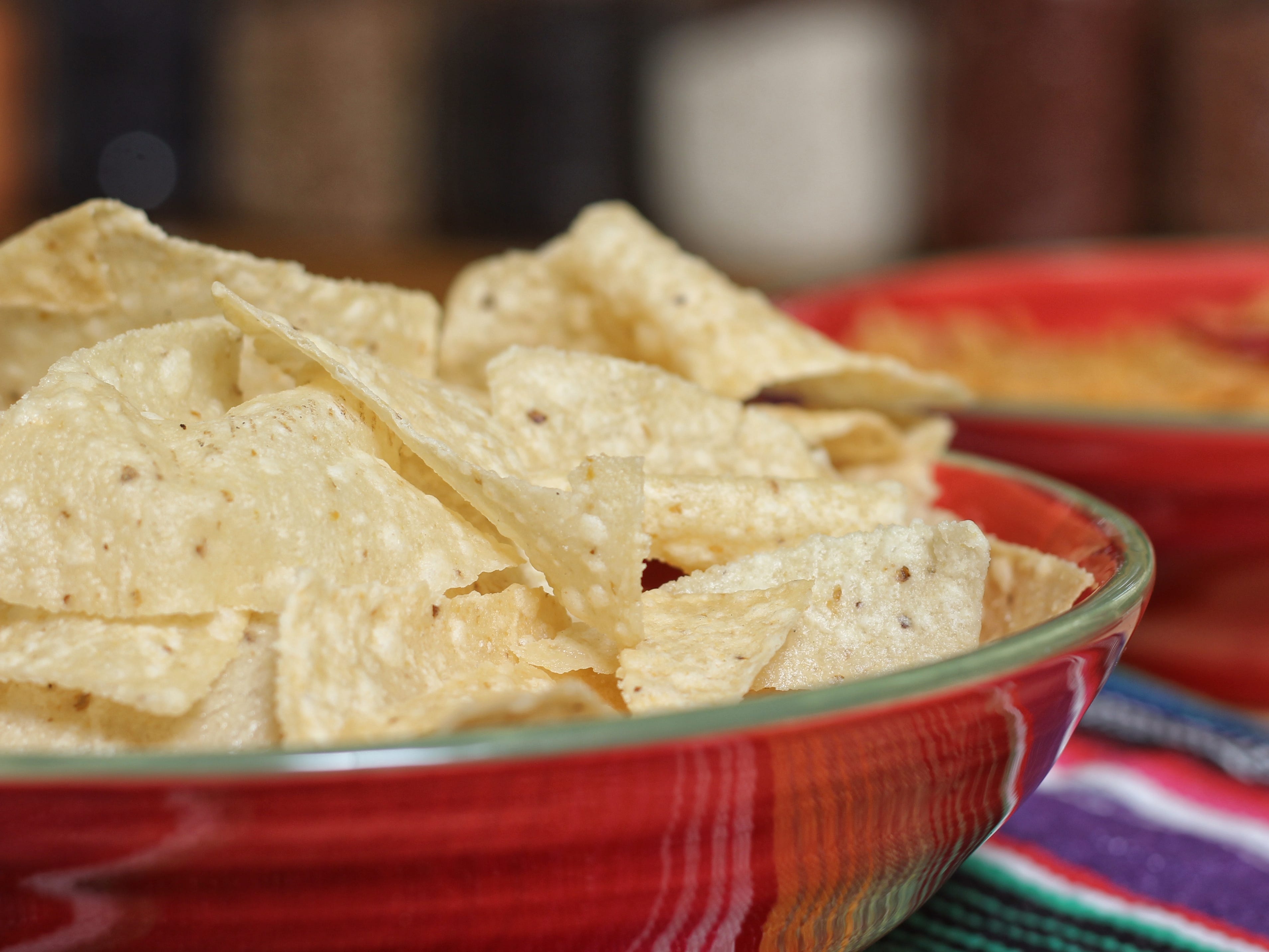 A bowl of tortilla chips on a table at a Mexican restaurant.