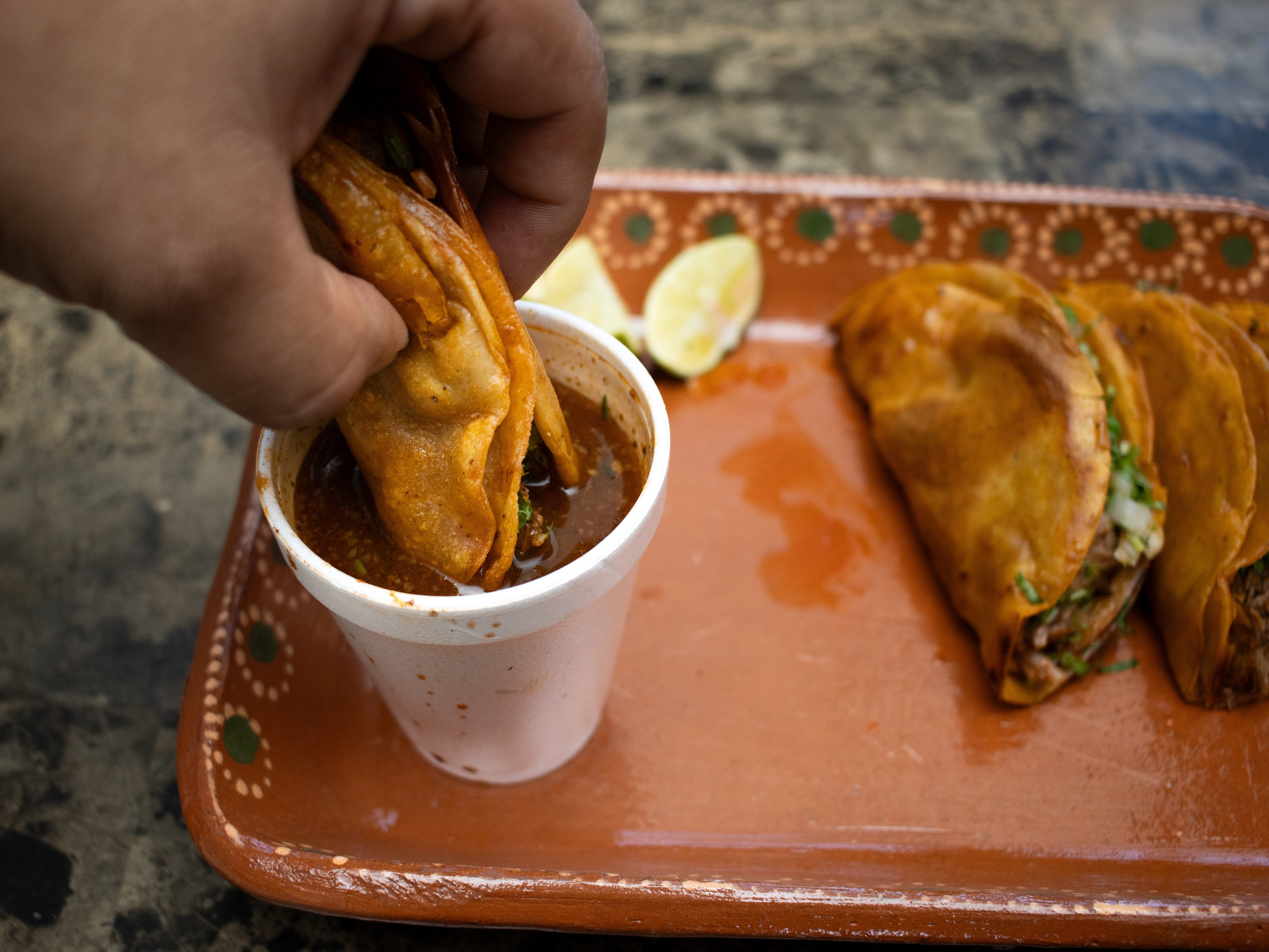 A hand dipping a taco in birra.
