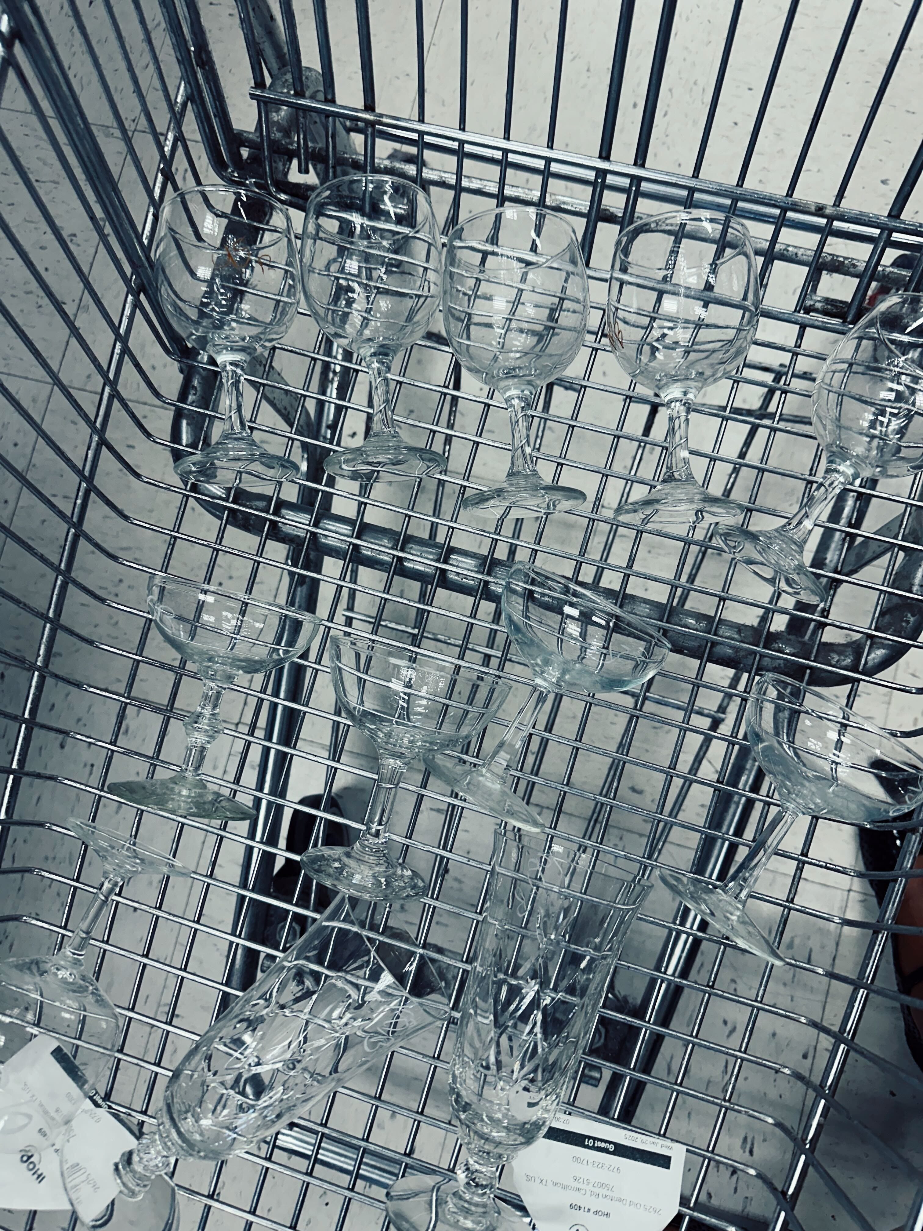 Glassware in a shopping cart at a thrift store.