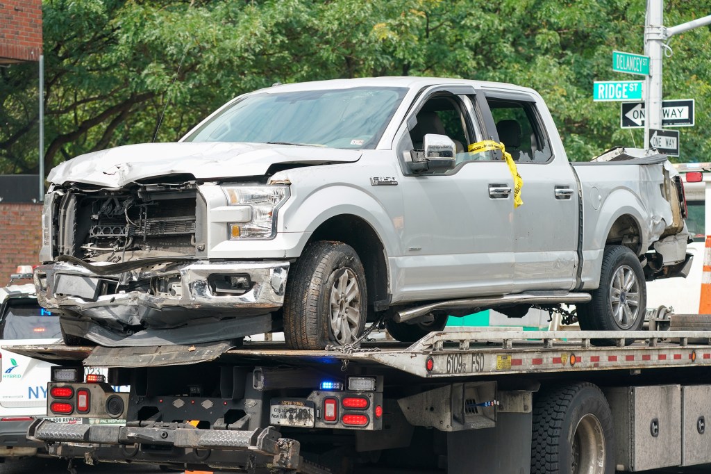 Damaged silver pickup truck on a tow truck, with 