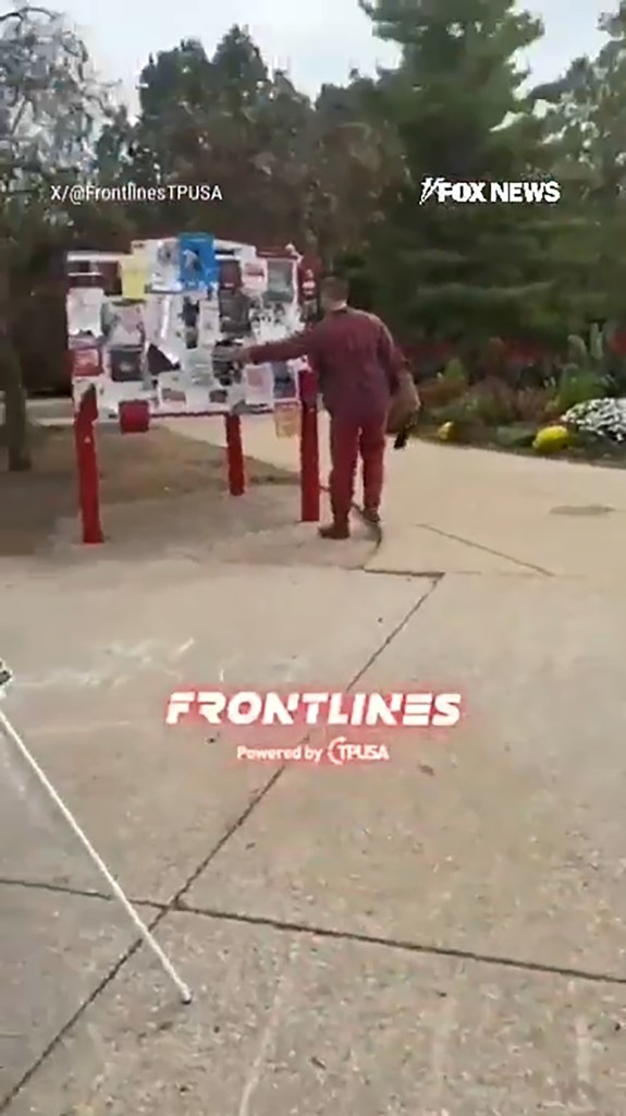 A person in a red outfit touching a display board covered with papers.