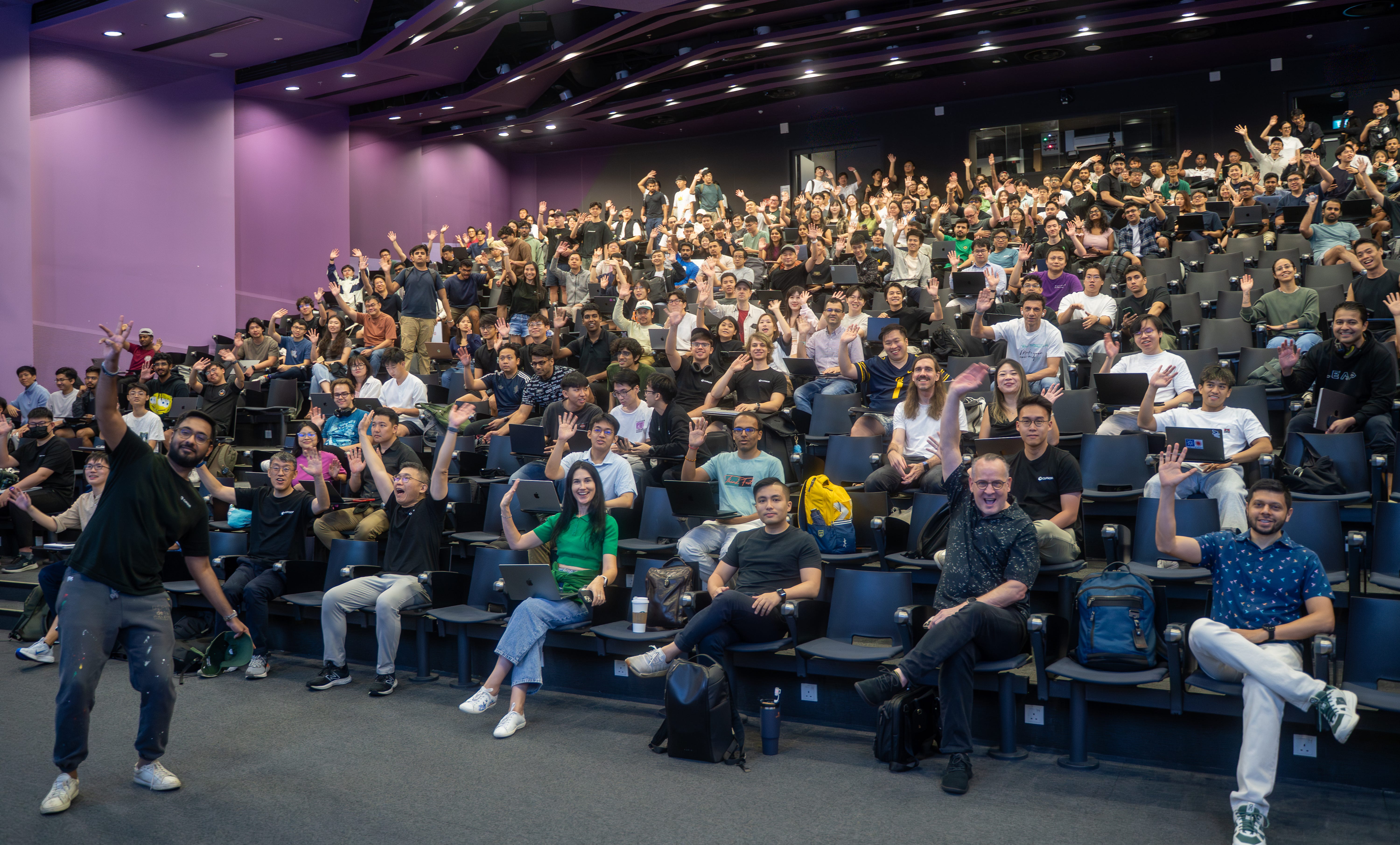 Students in a lecture theatre smiling at the camera