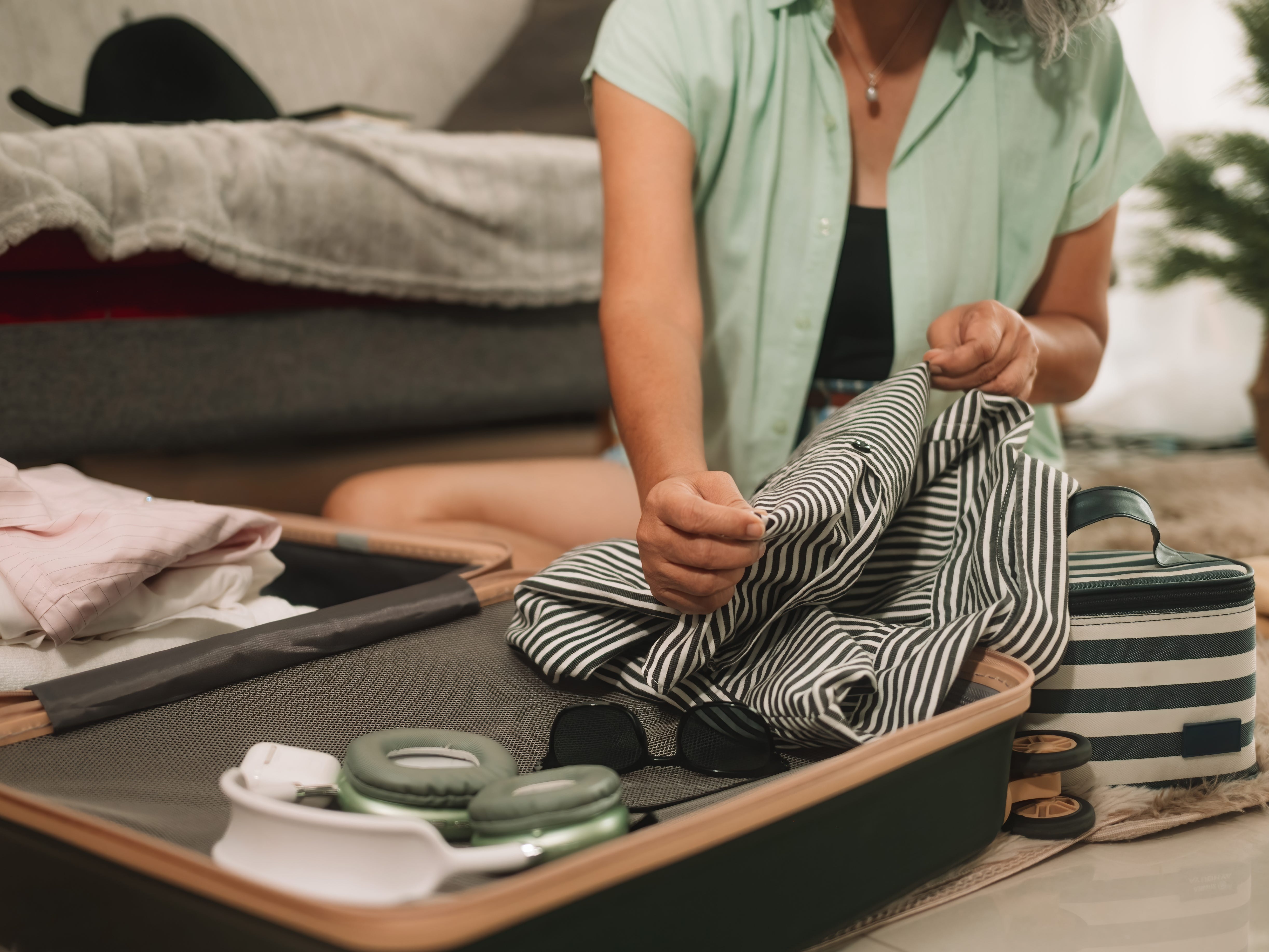 Close-up of a woman packing belongings in a suitcase.