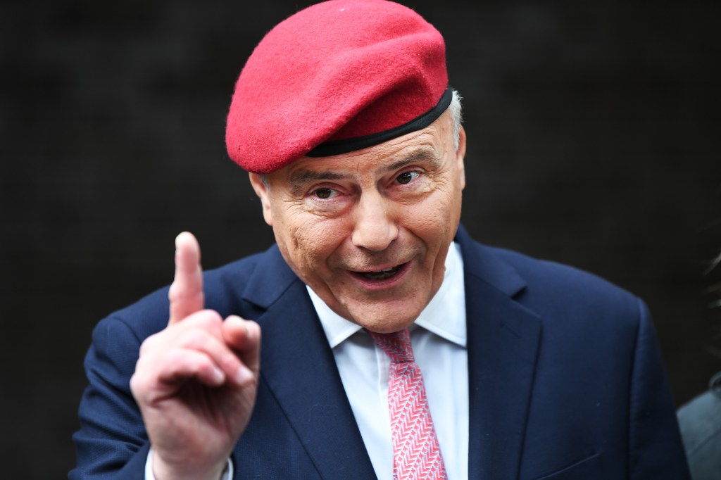NYC mayoral candidate Curtis Sliwa in a red beret and suit with his index finger raised.