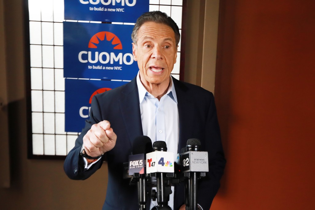 Mayoral candidate Andrew Cuomo at a press conference, speaking into multiple microphones.