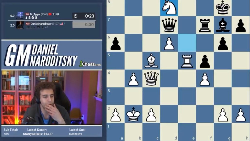 A man watching a chess game on a computer while streaming.