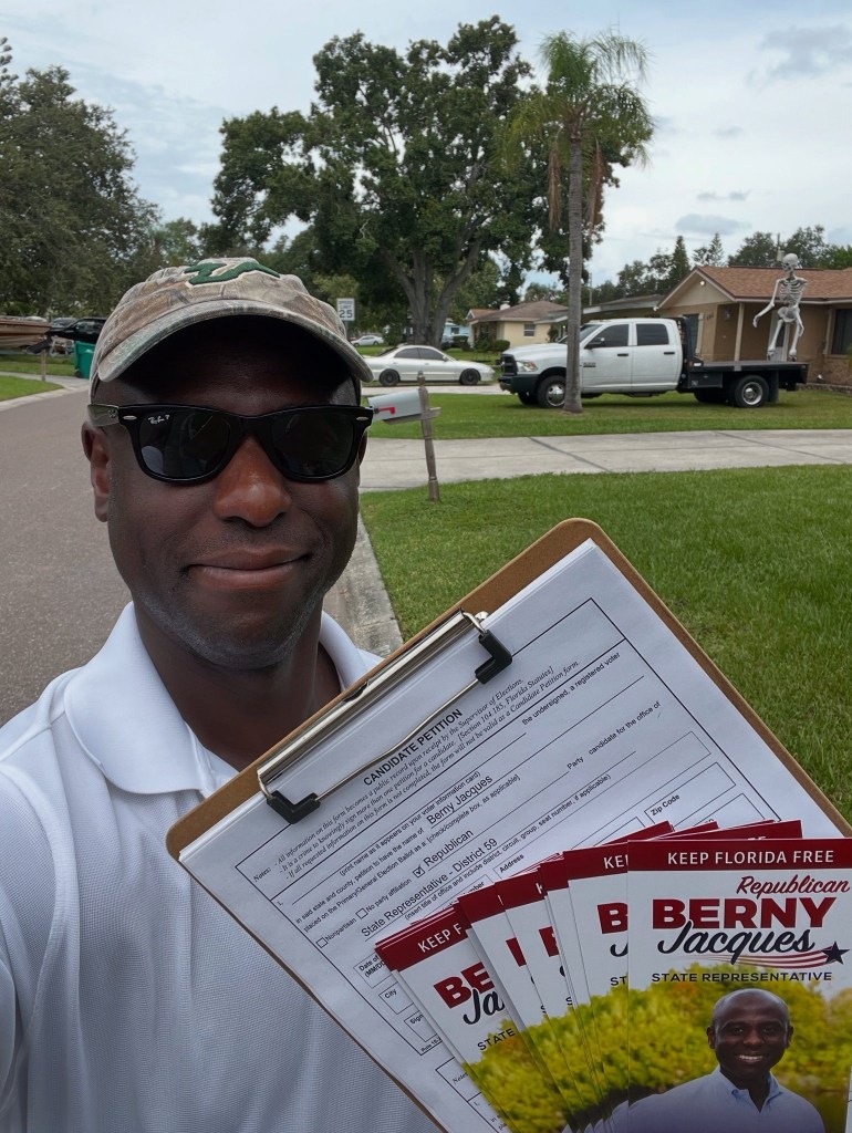 Man holding a clipboard with a candidate petition and campaign flyers for Berny Jacques.