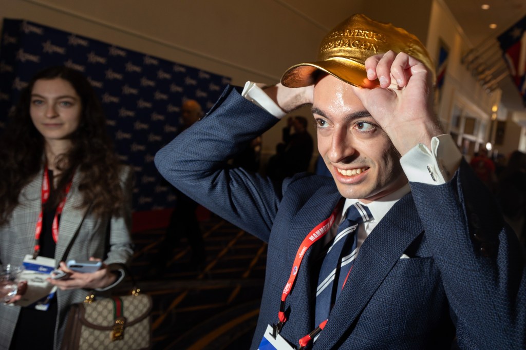 Paul Ingrassia tries on a bronze MAGA hat.