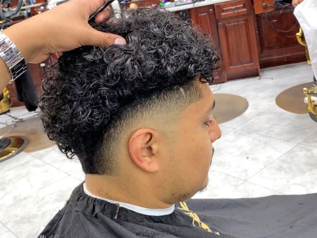 A man wearing a hairstyle with a burst fade and a curly top.