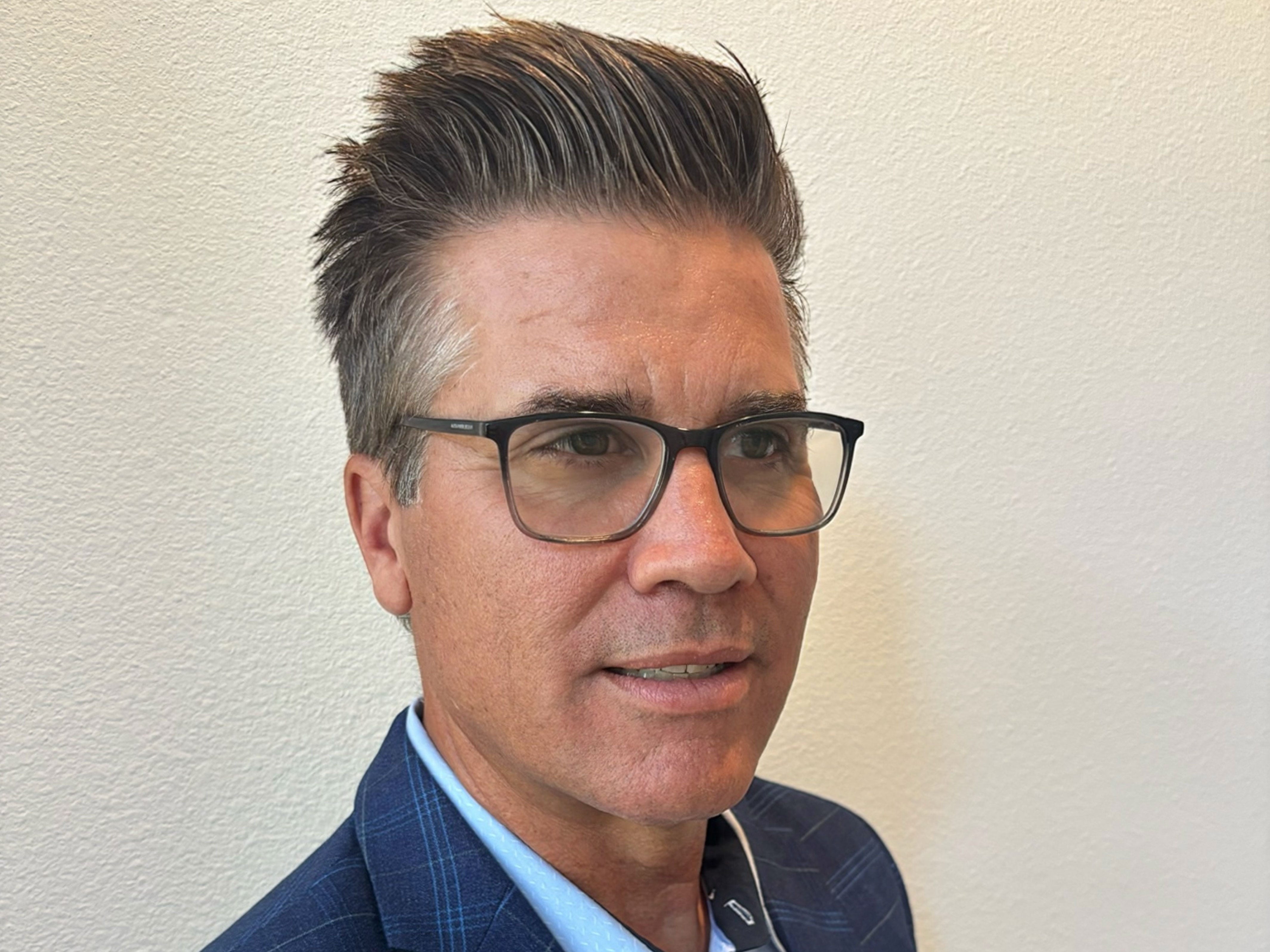A man with a hairstyle that has faded sides and a messy top.