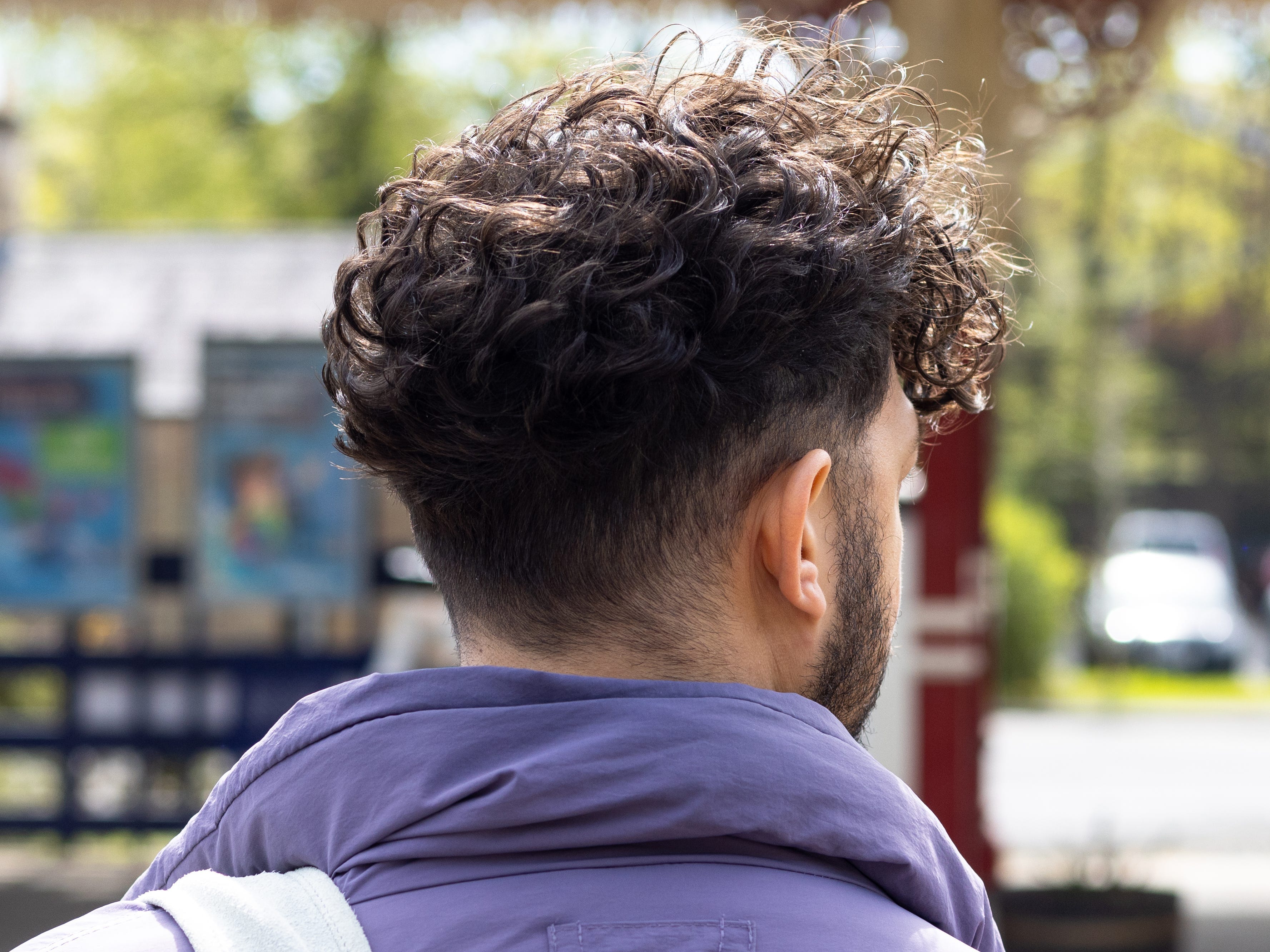 A man wearing a hairstyle that's tapered on the sides and curly on top.