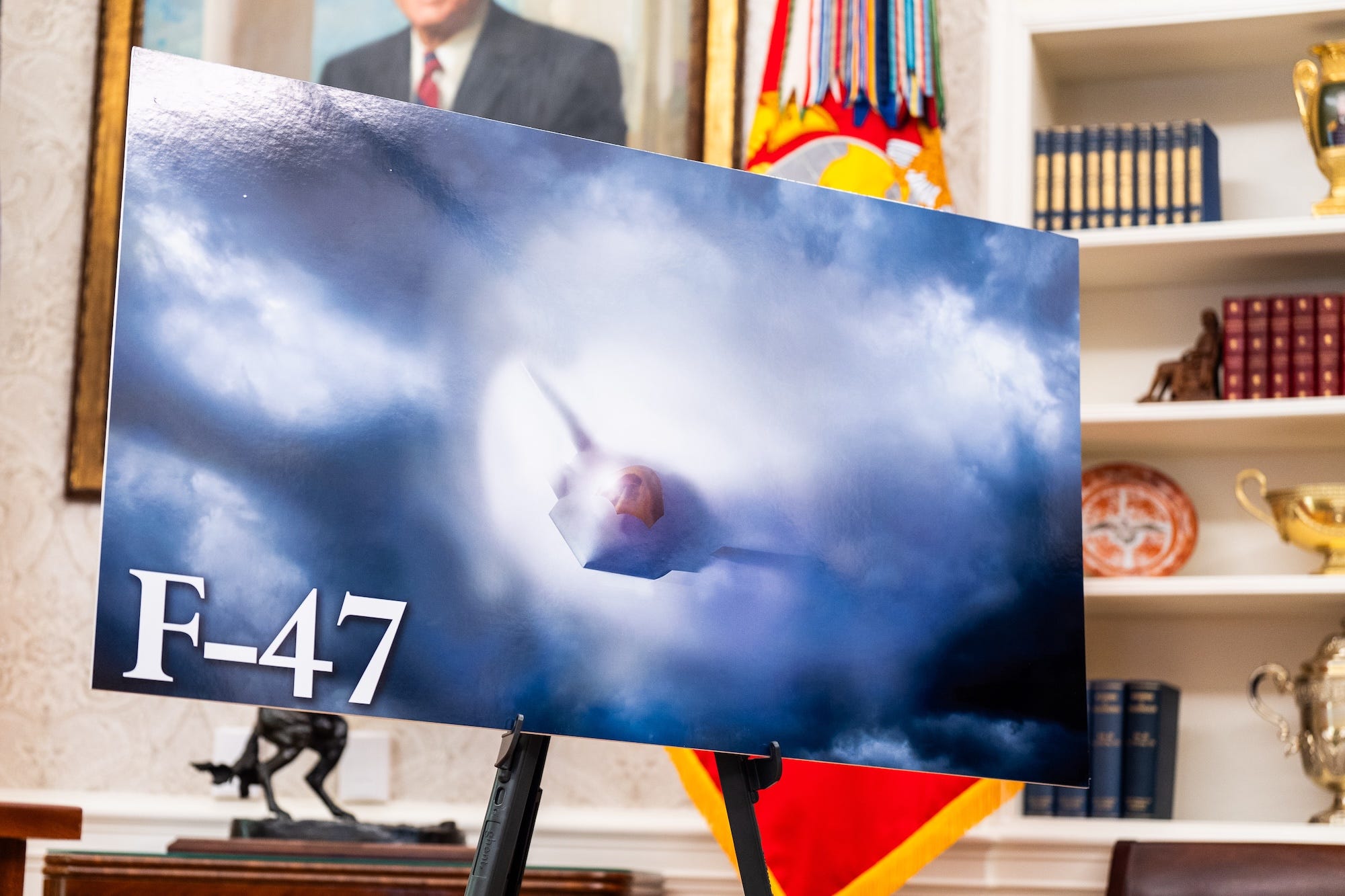 A concept image for a fighter jet in the air is on a stand in a formal room