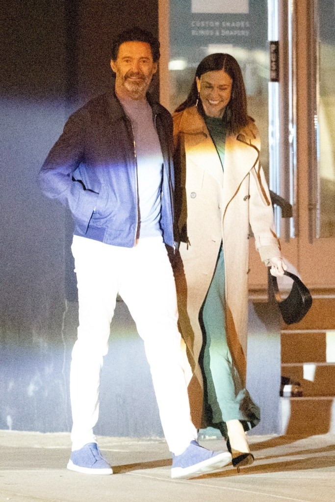 Hugh Jackman and Sutton Foster smiling as they walk arm-in-arm.