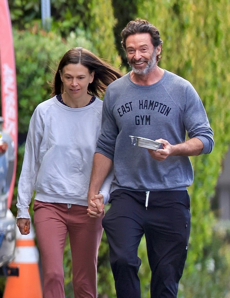 Hugh Jackman and Sutton Foster hold hands while strolling.